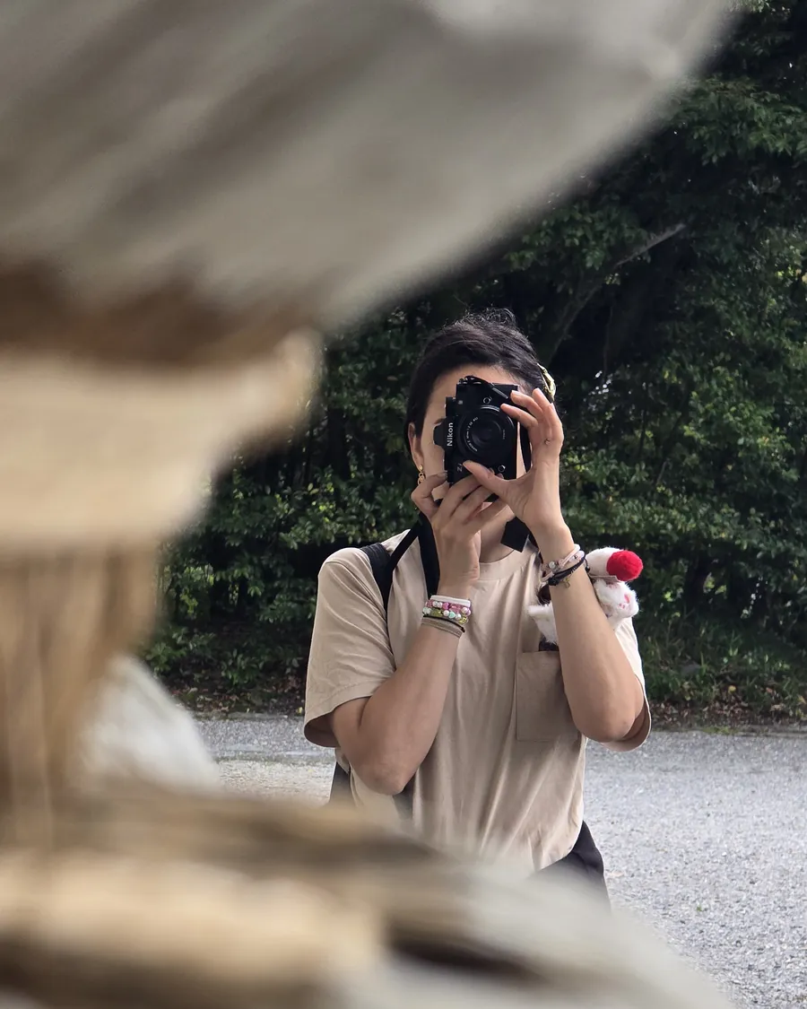 Sailor Nezel, son appareil photo Nikon devant le visage, en train de photographier dans un jardin japonais