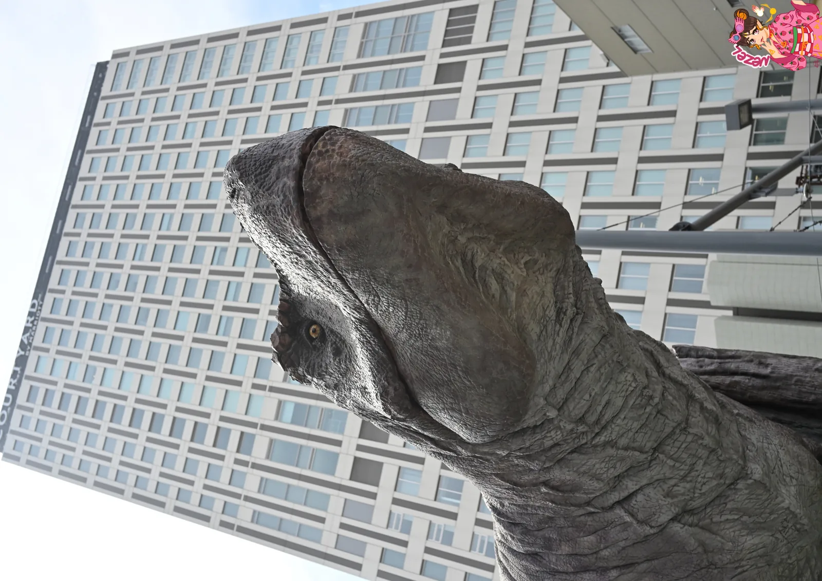T&ecirc;te d'un dinosaure gris &agrave; la gueule ouverte, dress&eacute; au pied d'un immeuble de Fukui