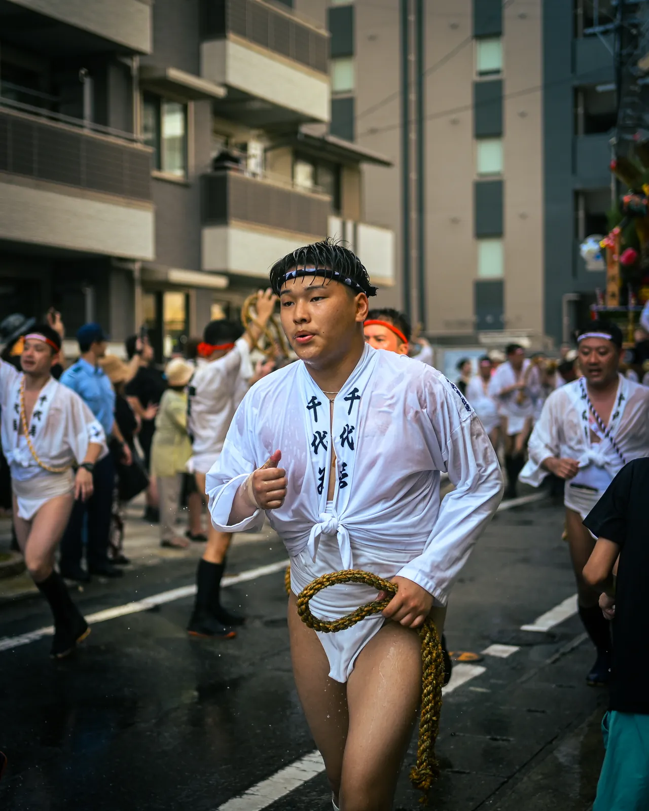 Participant en mizu-happi blanc trempé, courant dans la rue une corde tressée à la main