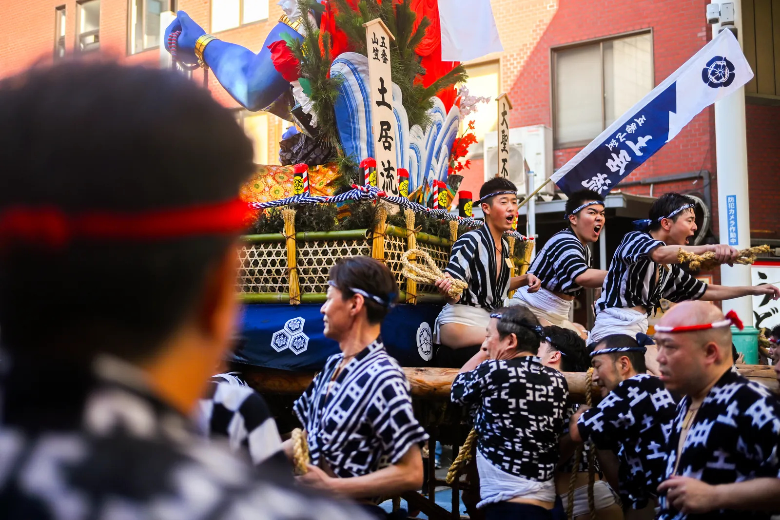 Hommes en mizu-happi portant un char Kakiyama sur leurs épaules dans une rue de Hakata