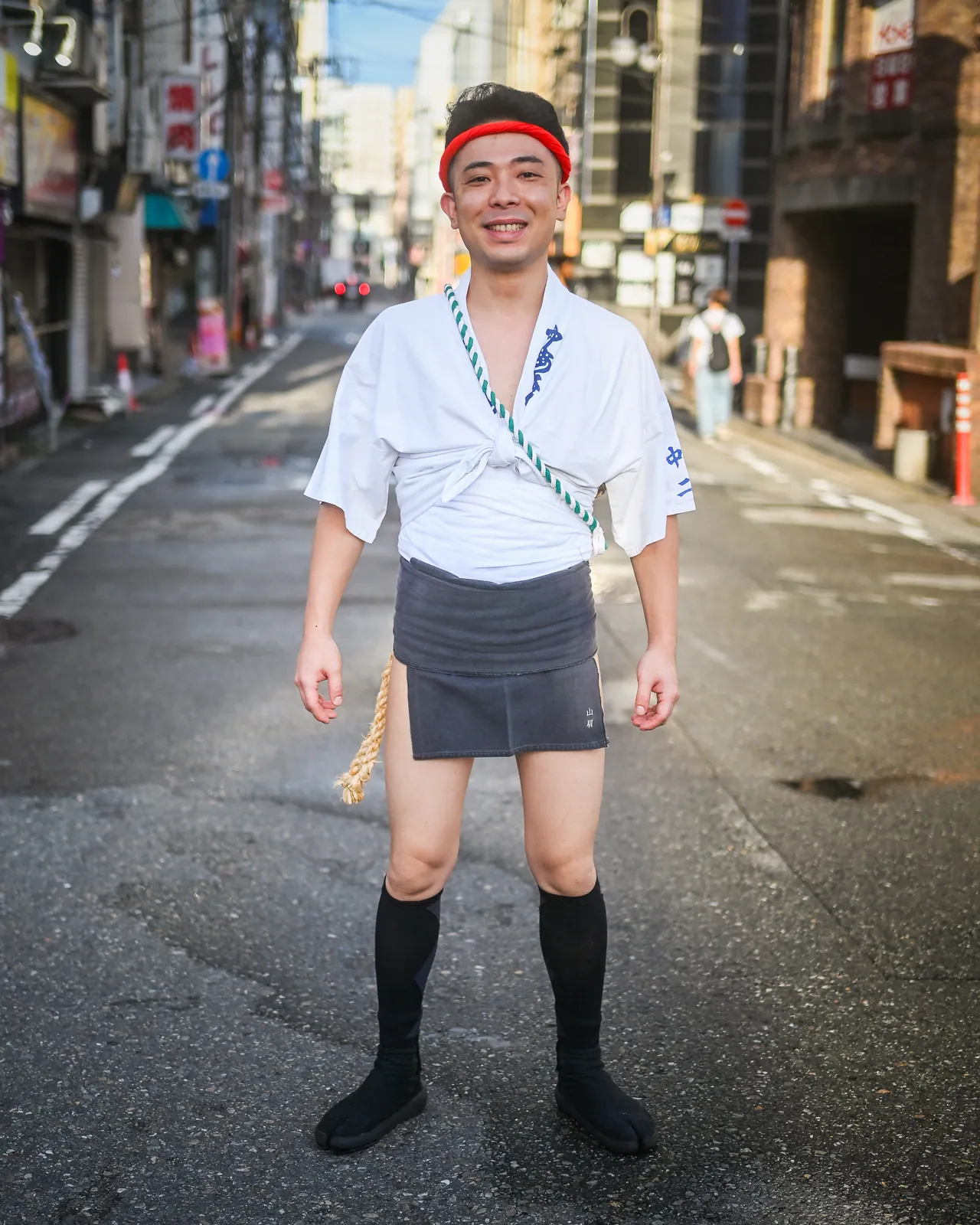 Participant portant le shimekomi, pièce de tissu nouée à la taille, dans une rue de Hakata