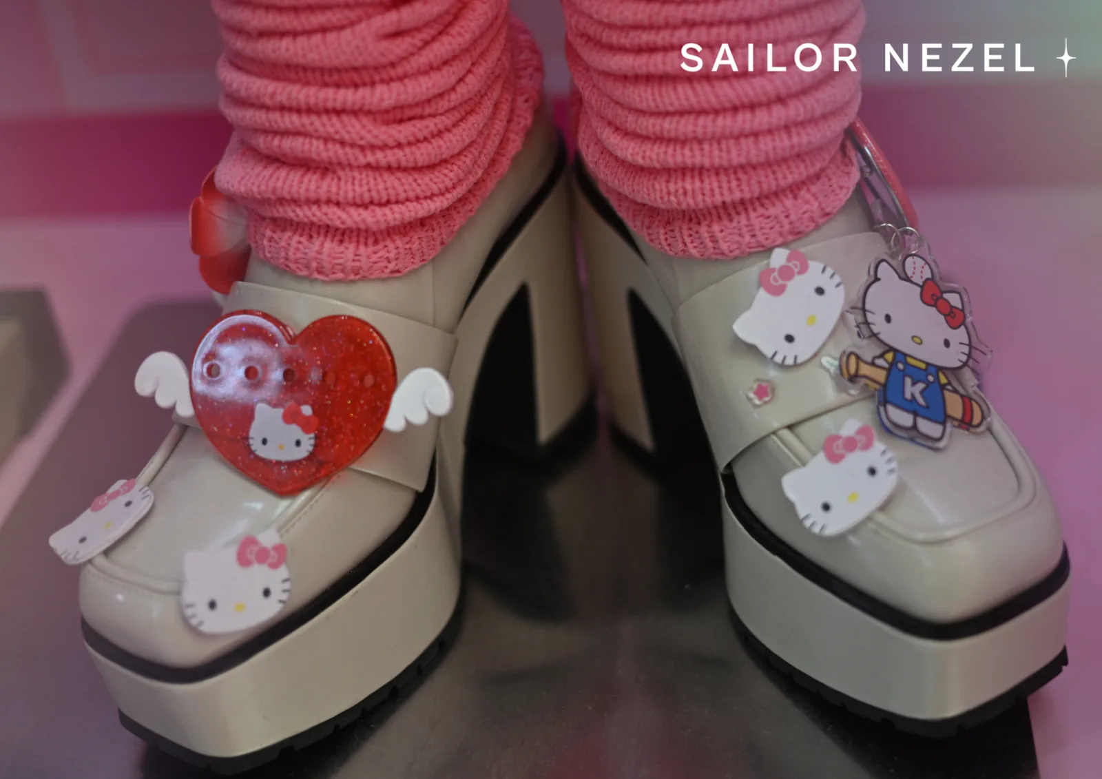 Chaussures à plateforme crème couvertes de badges Hello Kitty, dont un cœur rouge pailleté à ailes, portées avec d'épaisses chaussettes roses tombantes