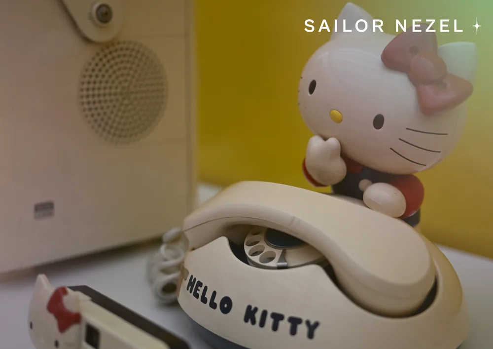 Téléphone fixe couleur crème portant l'inscription HELLO KITTY, surmonté d'une figurine du personnage