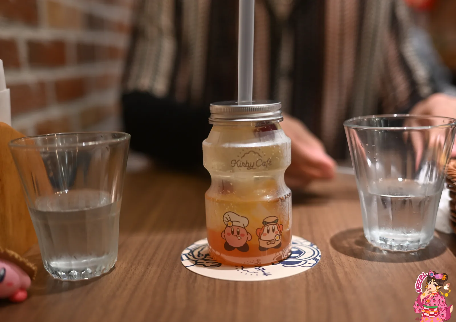 Boisson dégradée orange et jaune servie dans un bocal en verre siglé Kirby Café, posée sur un sous-verre