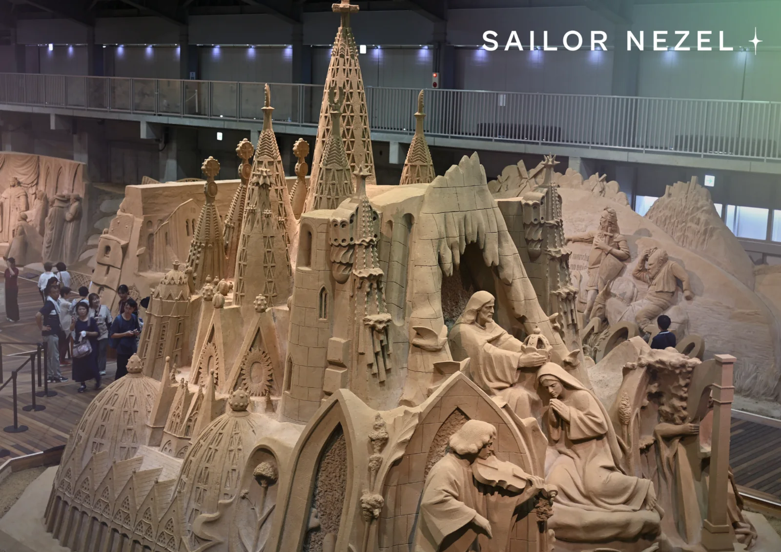 La Sagrada Família sculptée dans le sable, avec ses flèches et une scène de la Nativité, des visiteurs au pied de l'œuvre