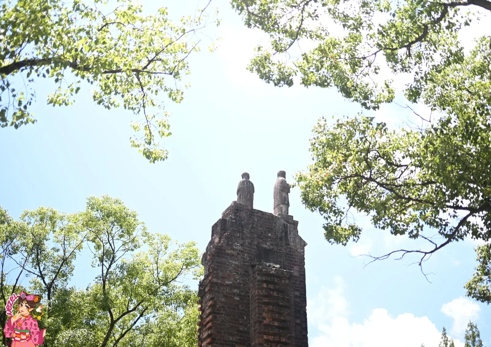Vestiges en brique de la cathédrale d'Urakami à Nagasaki, surmontés de statues, sous un ciel bleu