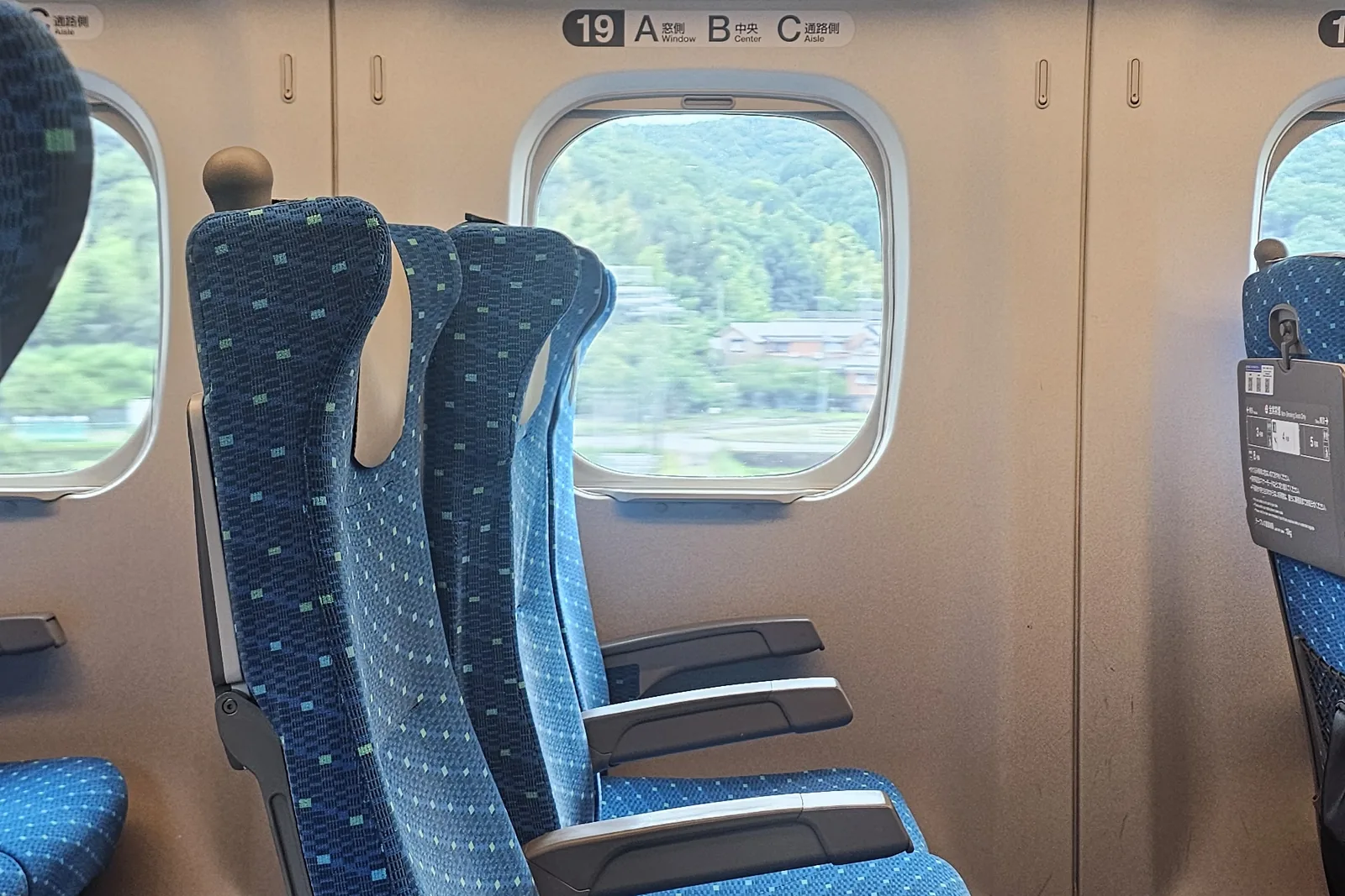 Intérieur d'une rame de shinkansen, sièges bleus alignés le long des fenêtres