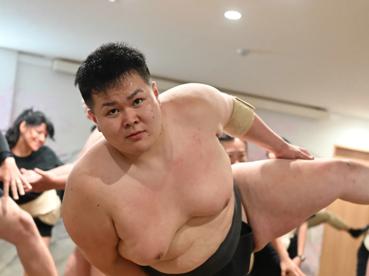 Un ancien rikishi l&egrave;ve haut la jambe pour d&eacute;montrer le shiko, le visage tourn&eacute; vers l'objectif