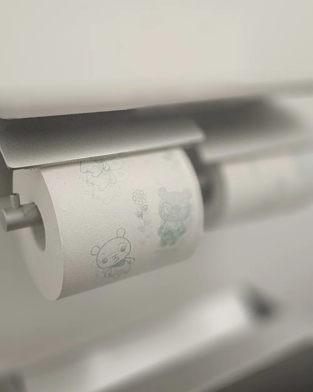 Rouleau de papier toilette imprimé de petits personnages, sur son dérouleur